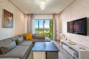 - un salon avec un canapé et une télévision dans l'établissement Luxury Living Flat in Prestigia Marrakech, à Marrakech