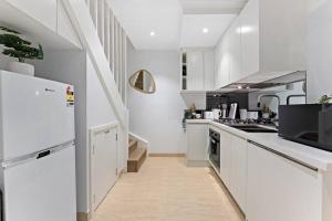 uma cozinha com armários brancos e um frigorífico em Beautiful 3BR House Close to Central Station em Sydney