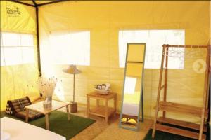 gelbes Zimmer mit einem Zimmer mit einem Bett und einem Tisch in der Unterkunft ไร่รื่นรมย์ Rai Ruen Rom Organic Farm in Ban Sawan