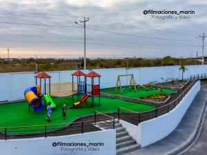 een speeltuin met twee kinderen op een groen veld bij Casa vacacional disfruta junto al mar in Manta