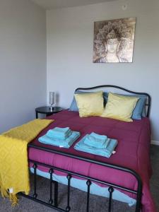 łóżko z fioletowym kocem i żółtymi poduszkami w obiekcie Luxury 1BR/1BA w/ Top Amenities in Prime Location w mieście Fort Wayne
