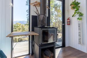 einen Kamin im Wohnzimmer mit Fenster in der Unterkunft Wallaby Cabin in Crackenback