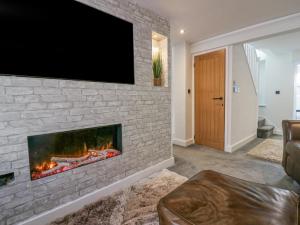 巴羅弗內斯的住宿－Crag View Cottage，客厅设有壁炉,砖墙上配有电视