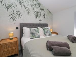 a bedroom with two beds and a wall with leaves at Crag View Cottage in Barrow in Furness