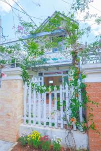 une clôture blanche devant une maison fleurie dans l'établissement Villa Hang Nga 2, à Đà Lạt