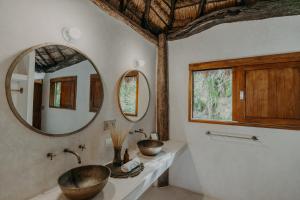 La salle de bains est pourvue de 2 lavabos et d'un grand miroir. dans l'établissement Sacred Hideaways, à Tulum