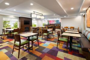 Fairfield Inn Concord في كونكورد: مطعم يحتوي على طاولات وكراسي على سجادة ملونة