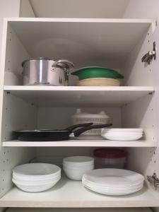 a kitchen shelf with plates and bowls and a pot at Studio cosy tout confort proche aéroport et Paris in Choisy-le-Roi