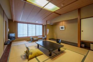 ein Wohnzimmer mit einem Tisch, Stühlen und einem Bildschirm in der Unterkunft Kaike Tsuruya in Yonago