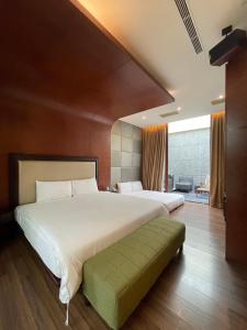 een slaapkamer met een groot wit bed en een groene bank bij G.SHOCK Motel in Pingtung City