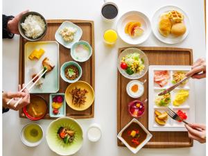 a table with plates of food and people holding chopsticks at Manza Kogen Hotel in Tsumagoi