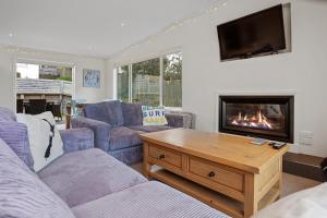 een woonkamer met een bank en een open haard bij Modern Kiwi Bach - Waihi Beach Holiday Home in Waihi Beach