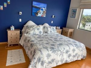 a bedroom with a bed with a blue wall at Bliss on the Beach - Whangapoua in Whangapoua