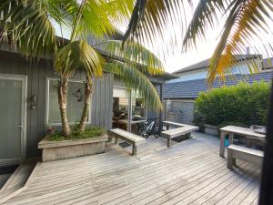 a wooden deck with benches and a palm tree at Bliss on the Beach - Whangapoua in Whangapoua