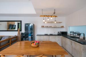 Una cocina con una mesa de madera con un bol de fruta encima. en Tepui Villa Canggu, en Canggu