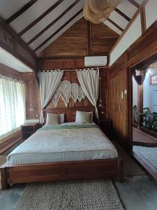 1 dormitorio con 1 cama grande y paredes de madera en Little Elephant Cottage, en Gili Trawangan