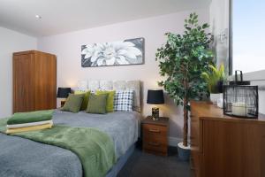 um quarto com uma cama, uma planta e uma cómoda em Cobalt Point 2 em Londres
