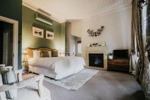 a bedroom with a white bed and a fireplace at Lake Daylesford Country House in Daylesford