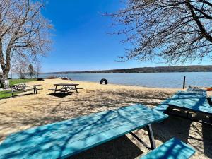 drie picknicktafels op een strand naast een meer bij New charming Lakeview Haven 2BR Cozy Como Cottage with Lake Views in Lake Geneva