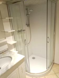 ein weißes Bad mit einer Dusche und einem Waschbecken in der Unterkunft Appartement d'une chambre avec terrasse et wifi a Brives Charensac in Brives-Charensac