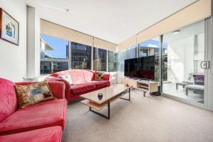 a living room with two red couches and a tv at Canberra Lakefront 2-Bed with Pool, Gym & Parking in Kingston 