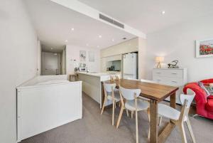 een keuken en eetkamer met een tafel en stoelen bij Canberra Lakefront 2-Bed with Pool, Gym & Parking in Kingston 