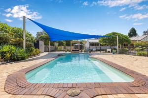 una piscina con un dosel azul sobre ella en Bon Villas B&B Bonville en Coffs Harbour