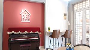 a red wall with a piano in a living room at REDHOME DORM in Ho Chi Minh City