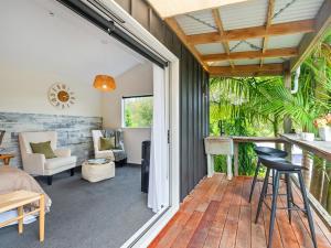 a room with a balcony with a bed and a table at Country Idyll - Sandspit Holiday Cottage in Sandspit