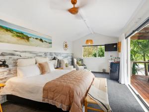 Country Idyll - Sandspit Holiday Cottage في Sandspit: غرفة نوم مع سرير كبير وشرفة