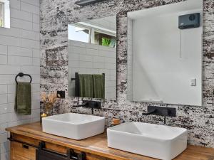 Country Idyll - Sandspit Holiday Cottage في Sandspit: حمام به مغسلتين بيضاء ومرآة