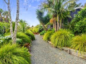 a garden with palm trees and a gravel path at Country Idyll - Sandspit Holiday Cottage in Sandspit