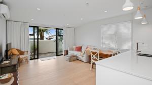 a kitchen and living room with a couch and a table at Residence De La Mer - Orewa Holiday Home in Orewa
