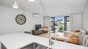 a kitchen and living room with a couch and a table at Residence De La Mer - Orewa Holiday Home in Orewa