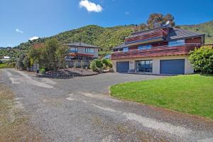 a house with a driveway in front of a mountain at Waimarama Hideaway - Waikawa Holiday Home in Waikawa