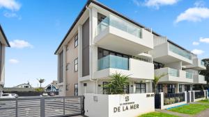 an apartment building with a white facade at Residence De La Mer - Orewa Holiday Home in Orewa