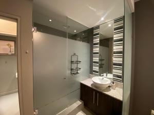 a bathroom with a sink and a glass shower at Luxurious 2 Bed @ The Tyrwhitt in Johannesburg