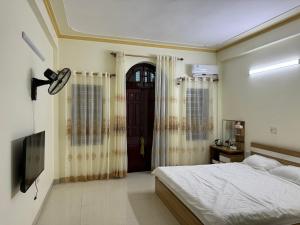 1 dormitorio con 1 cama y una puerta con cortinas en Nhà Nghỉ Hương Sen en Móng Cái