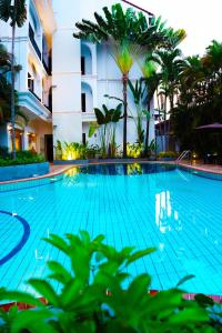 a swimming pool in front of a building with palm trees at ANGKOR TRAILS Residence in Siem Reap