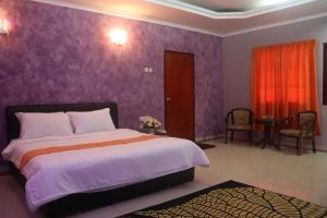 a bedroom with a large bed with purple walls at Bunga Raya Resort Parit Buntar in Parit Buntar +21 photos
