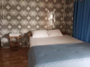 1 dormitorio con 1 cama y una pared con cortinas azules en Noppakao Resort, en Soem Ngam