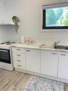 a kitchen with white cabinets and a sink and a window at Marysville Holiday Park in Marysville