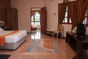 een slaapkamer met een bed en een tv in een kamer bij Bunga Raya Resort Parit Buntar in Parit Buntar