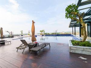 a swimming pool with two chairs and a umbrella at Lovina 2103 at Pollux Meisterstadt in Batam Center