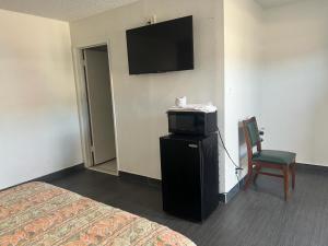 a room with a bed and a tv and a chair at Pomona Inn in Pomona