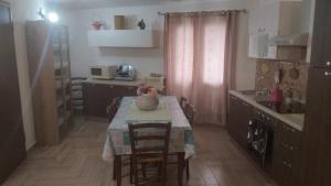 cocina con mesa, sillas y fregadero en Su Cuccureddu ONIFAI, en Onifai
