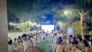 een groep mensen die aan tafel zitten in een restaurant bij Villa FLC Sầm Sơn Ngọc Trai - Ngay Gần Biển in Sầm Sơn