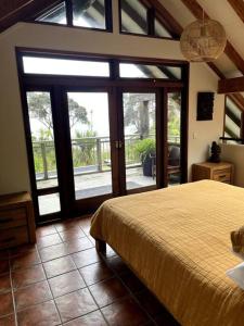 1 dormitorio con 1 cama grande y puertas correderas de cristal en Whananaki Hideaway, 