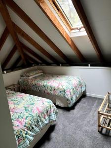 a attic room with two beds and a window at Whananaki Hideaway 