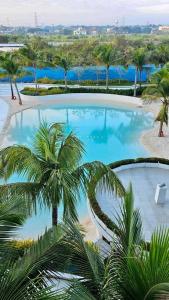 uitzicht op een groot zwembad met palmbomen bij Urban Zen at Azure North Pampanga - Studio 416 NA in Lagundi